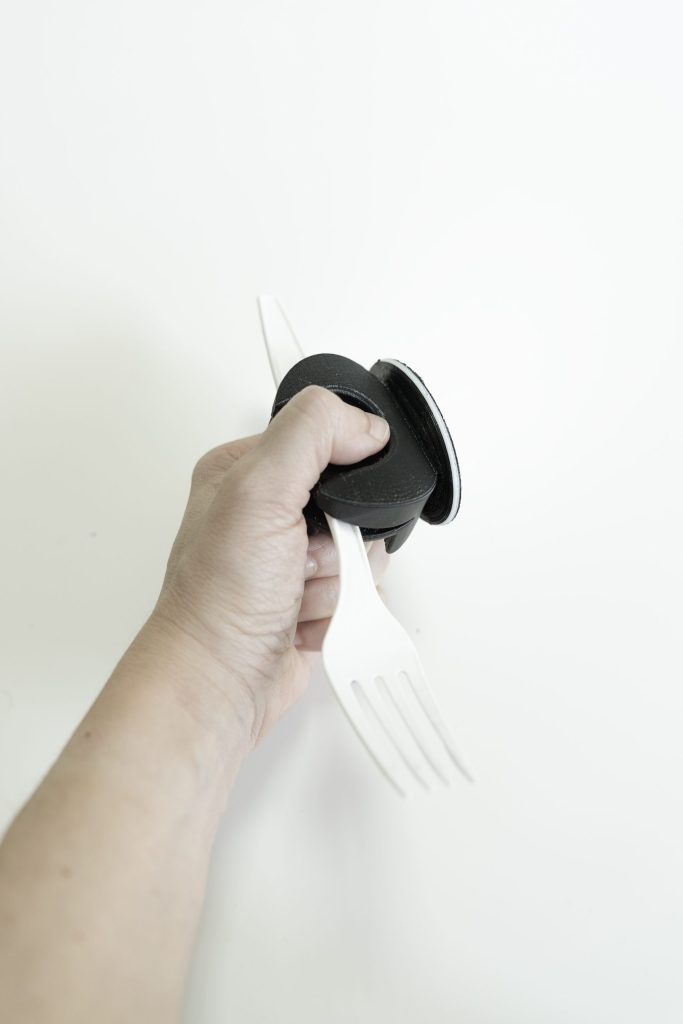Una mano sujetando un engrosador impreso en 3D con un cuchillo.