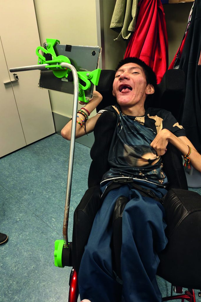 Chico en silla de ruedas utilizando un soporte para tablet impreso en 3D